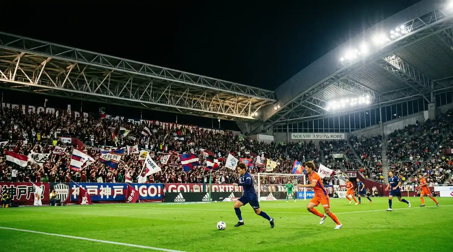 Estadio de fútbol japonés iluminado durante un partido nocturno de la J-League